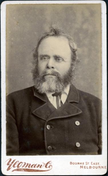 This image is of the head and shoulders of a man wearing a double-breasted coat.  He has large side-leavers with a beard and moustache.  He has a serious look on his face.  Printed at the bottom of the photograph is: “Yeoman & Co Bourke St. East Melbourne”.
