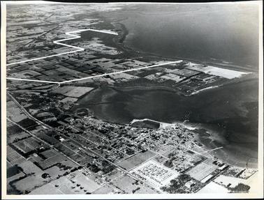This image shows an aerial photograph of a town, farming lands and a shoreline.  A large area of the land has been marked out in white lines.  Two jetties can be seen at the lower right-hand side and many boats can be seen in the water.  The number 15412 is written on the back in black pencil.