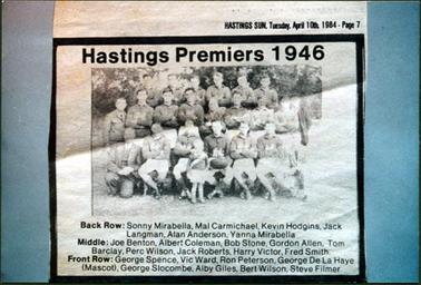 This image is a photograph from a section of the Hastings Sun, Tuesday, April 10th, 1984 - Page 7.  It is of the Hastings Premiers 1946.  This information, along with the names of the players, is printed on the image.  The team is in three rows, posing for a photograph.  There are six men standing on a form in the back row, nine men standing in the middle row and seven men sitting on chairs or kneeling in the front row.  A small boy is standing in front of the team. Everyone is in football uniform except for four men who are wearing suits.  A player in the front row has a football on his lap. Tall trees can be seen in the background.  