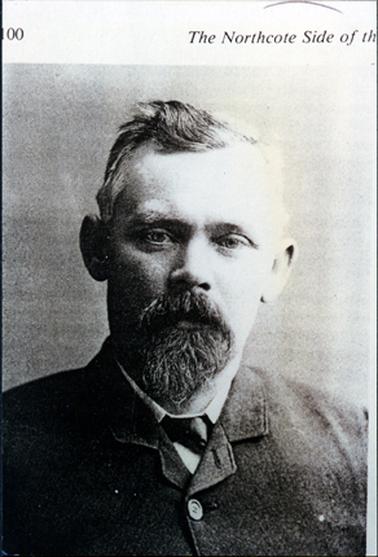 This image shows the head and shoulders of a man.  He is looking straight at the camera, but not smiling.  He has a thick greying moustache and beard.  His greying hair is parted on the left side.  He is wearing a white shirt, black tie and his dark coloured coat is buttoned up almost to the neck.  Printed across the top of the photograph is “00 The Northcote Side of th’.  