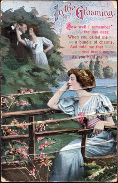 This colour postcard shows a young woman sitting beside a post and rail fence.  Her elbow is resting on the top rail of the fence and her hand is against her face.  She has a ‘dreamy’ look on her face.  She is dressed in a blue dress with a large pink rose on the front.  Pink flowers are along the fence and water and trees are in the background.  Her image, along with that of a man, is in the trees on the left-hand side of the image.  The verse printed on the postcard reads as follows: “In the Gloaming.  How well I remember the day dear, When you called me a bundle of charms, And told me that you loved me, As you held me in your arms.”