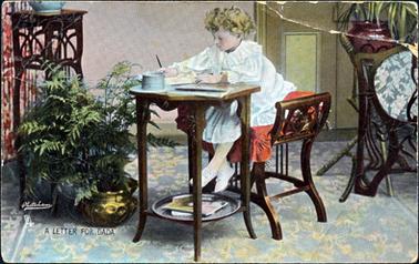 This image shows a little girl sitting at a small table.  She is sitting on a red cushion on a carved stool.  She appears to be writing a letter.  There is a round tray at the bottom of the table.  Her feet don’t touch the floor.  She is dressed in a white tunic with frills at the neck, wrists and around the bottom of the skirt.  She has blonde curly hair.  A large gold coloured pot with ferns is on the floor and other pieces of furniture can be seen on either side.  A patterned carpet is on the floor.  The following is printed at the bottom of the image: “A LETTER FOR DADA Photochrome”.