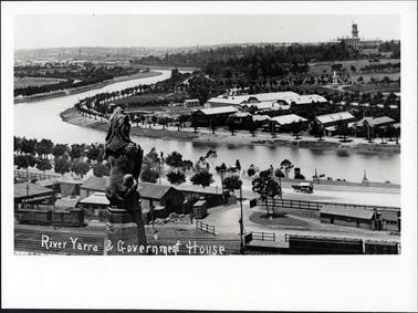 This image shows a river winding through a city.  Trees line both sides of the river banks.  Railway wagons, tracks and buildings can be seen.  Part of a statue is in the foreground.  A very large building with a tower is in the far right-hand corner of the image.  A horse-drawn wagon is on the street.  Printed in white across the bottom of the image is: “River Yarra & Government House”.