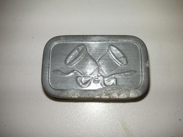 Small tin with imprint of wedding bells on top and bottom.  Lined with cardboard.