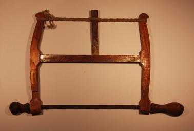 Wooden framed bow saw with replaceable metal blade and string tensioner.