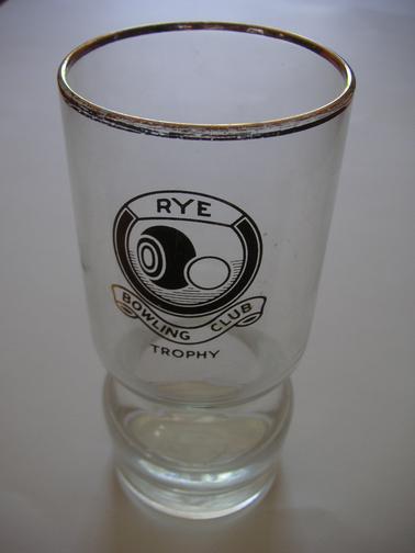 Rye Bowls Club trophy in the form of a drinking glass.  Fluted 8cm from top and 3cm from base.  Gold around the top and the words “RYE BOWLING CLUB TROPHY” in gold lettering on the side.