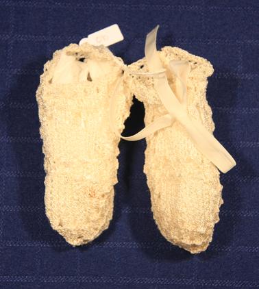 1 pair white baby booties with ribbon.