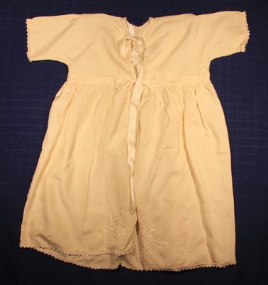 White silk baby carry coat. Crocheted around edges and sleeves. Ribbon ties at neck and waist.  Handwork in 4 places on front.
