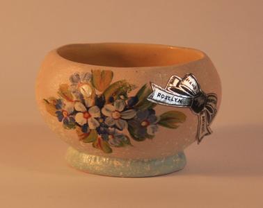 Small pottery oval vase with rough cream and duck-egg blue base.  Pink with floral pattern one side.  Yellow inside.