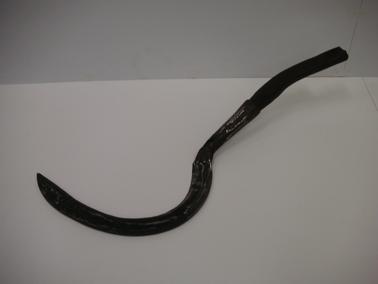 Metal sickle with wooden handle.  Left handed.  Illegible letters into the metal shaft At some stage painted orange.