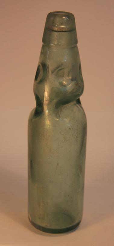 Clear light green glass  bottle with glass marble stopper.  Heavily indented in top 3rd of bottle. 