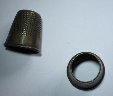 Two brass thimbles used to protect fingers when hand sewing.  One has open end.