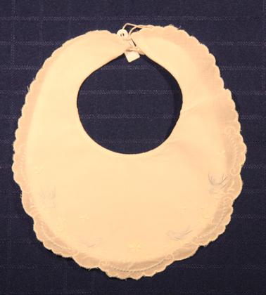 New white baby bib. Scalloped edge, blue birds interspersed with white flowers near edge