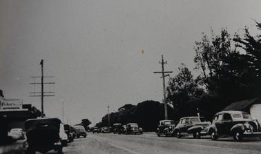 Nepean Highway looking west from Hygeia Street, Rye.  Cars parked on both sides of highway. 