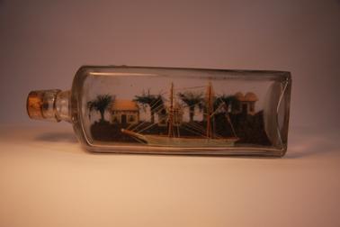 Two masted sailing ship in bottle.  Model houses and church at back.
W & A Gilbey bottle for “Silver Stream Schnapps”