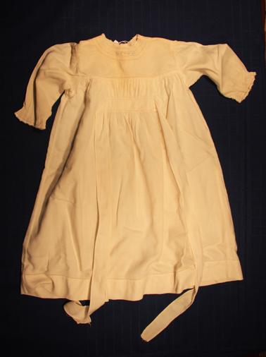 Cream baby nightdress. Long sleeves. Crocheted neck and wrist. Fancy work. Roses at neck.
M. C. Honan name tag inside hem.