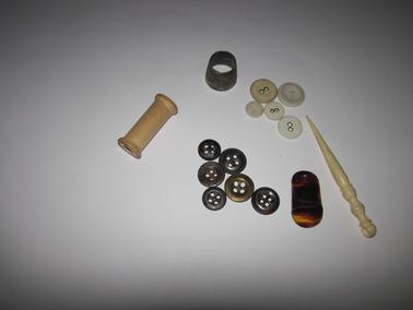 Old buttons:  covered buttons for men’s underwear,  trouser fly buttons; cotton reel, silver thimble, plastic finger protector, lace making implement