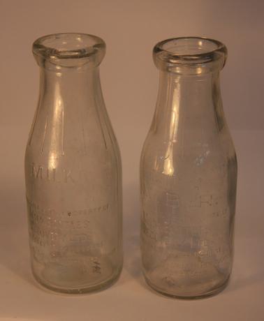 2 clear glass milk bottles.  (Cardboard cap type).  Inscription reads: “M.B.R. Milk Bottles Recovery”.