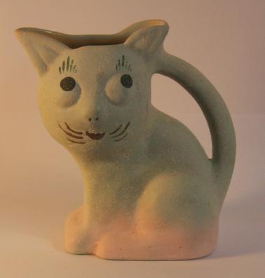 Rough textured pottery jug in cat form.  Painted cat face on one side.  Pink and green colour.