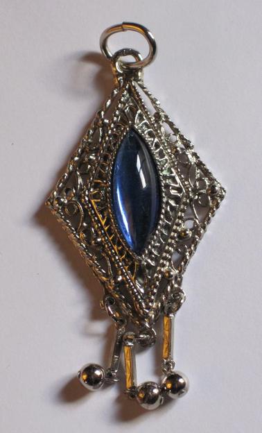 Diamond shaped pendant.  Metal - silver coloured, with oval shaphire blue glass (lengthways) in centre.  Three 3cm extensions hanging from base.  Ring at top for chain to go through.