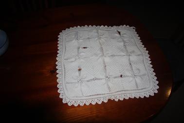 Square knitted cotton table mat with crocheted edges.  Natural colour.