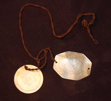 2 dog tags with string.  
1 round: Engraved top around edge: Sullivan, A.J. V 215945: Centre circle RC 04;  Reverse: MFO NT in 6 pointed star 1942
1 rectangle with corners cut.  Engraved.  Top around edge: Sullivan A.J. V215945; crossed flags in centre Union Jack and AUSTN.  RC 04;  Reverse: yacht on water Darwin at base.