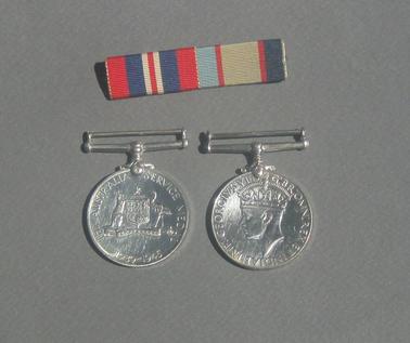 2 war service medals with holder on top attached with claw fitting to medal. Ribbon separate. War medal has George VI front and lion and eagle on reverse.  Australian Service medal has George VI on front and Australian Coat of Arms on reverse.  Contained in plastic box with “Siemens” logo on front