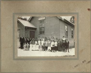 Rye schoolchildren outside the 1875 school building in 1920.  Head Teacher (Mr Moody) on left and Sewing Mistress (Grace Sullivan) on right.