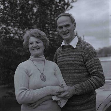 A man and woman in winter clothing photgraphed outdoors.