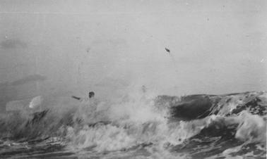 Surf breaking. Two people just visible, heads and an arm.