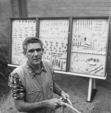 Man holding a rope with a rope knots display in the backgrouno date.