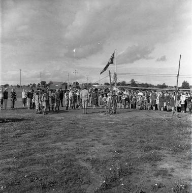 A group of Scouts, Girl Guides and Brownies on a field.
