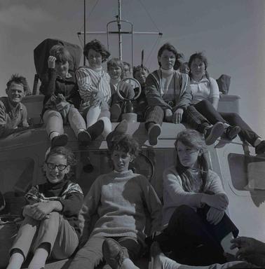 A group of chilldren sitting on the cabin roof of a boat.
