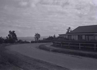 A road corner with  view to the Bay and a building on the right in the bend of the road.