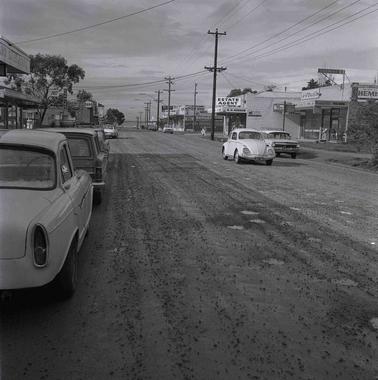  A view along a street with shops and cars.street 