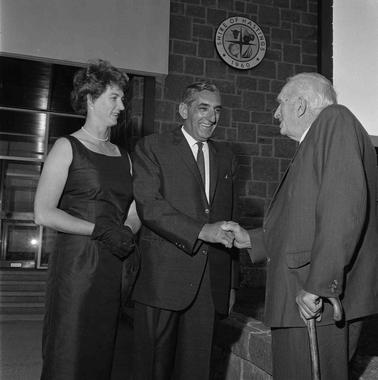 A woman and two men shaking hands.