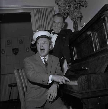 Two men at a piano | one is performing.