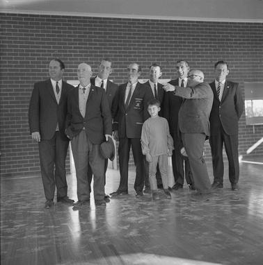 Eight men in suits and a boy lined up for a photograph.