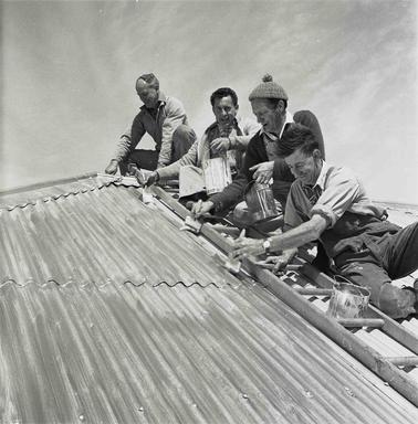 Four men repairing a corroguated iron roof.