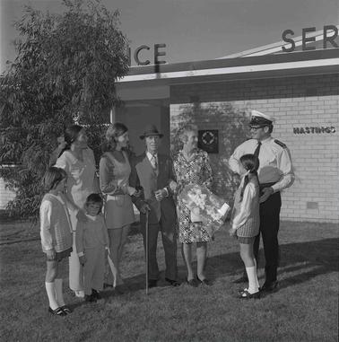 A group of seven adults and children talking to an ambulance officer.