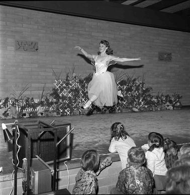 A young woman in ballet costume dancing on a stage.