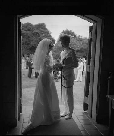A bridal couple framed by the door of a church as the photo was taken from the inside.