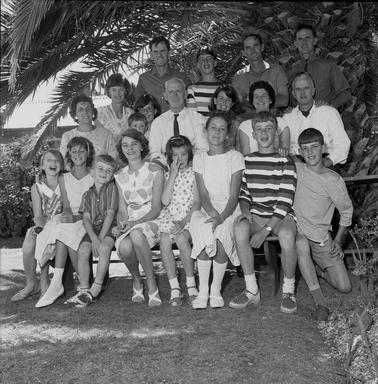 A group of adults and children posing for an outdoor photograph in three rows.