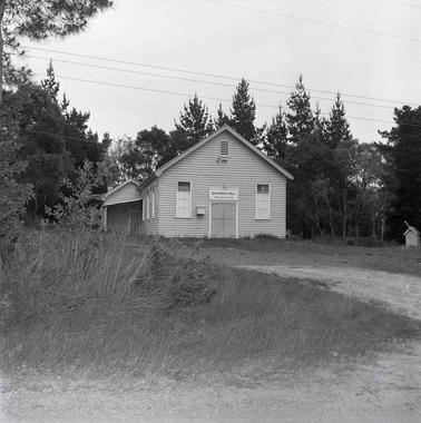 Weatherboard building with centre door and windows either side.  Three more windows on the left side wall.  An adjoining smaller building is behind and attached. Signage above the door reads: Balnarring Hall, Opened August  18th,1898.