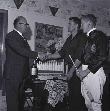 A jockey and another being congratulated by a third man.