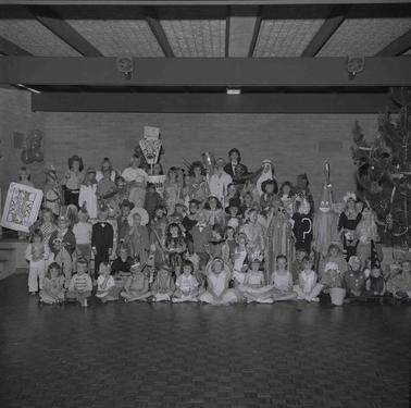 A tableau of around seventy children in fancy dress costume posing in five rows for a photograph.