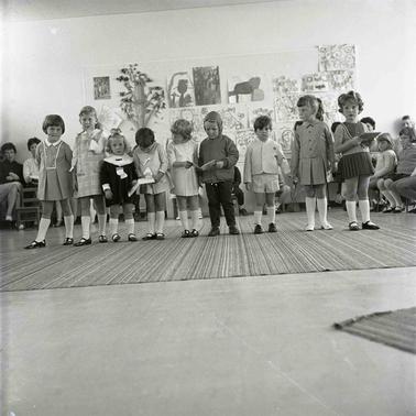 Nine children lined up on a stage.