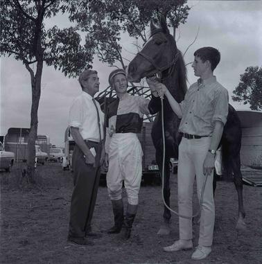 Three Men with a horse, one is wearing a jockey’s garb.