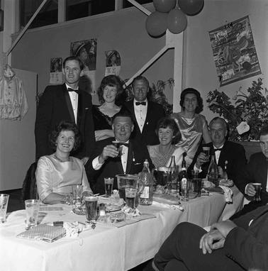 Four men and four women with others at a formaldinner table: a celebatory event.