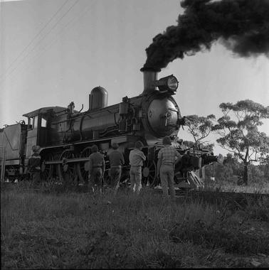 Five young boys looking at a steam train engine.